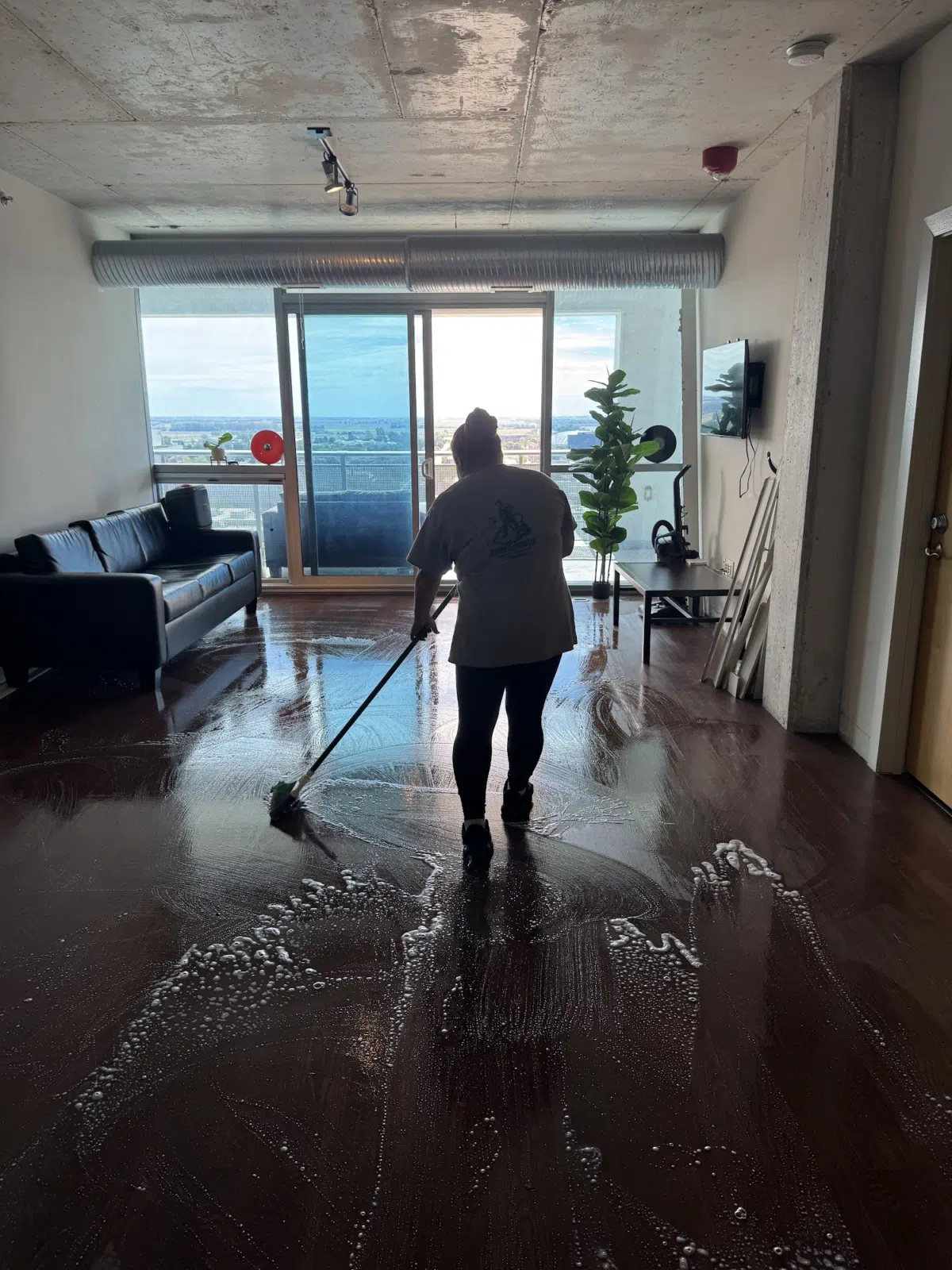 Cleaner mopping a foamy hardwood floor in a high-rise apartment — Leskuin Cleaning LLC in Springfield